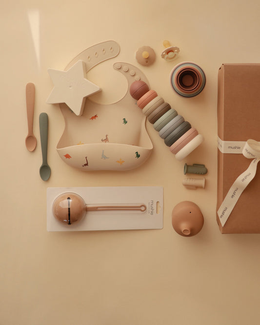 Collection of baby toys and a wrapped gift on a beige background