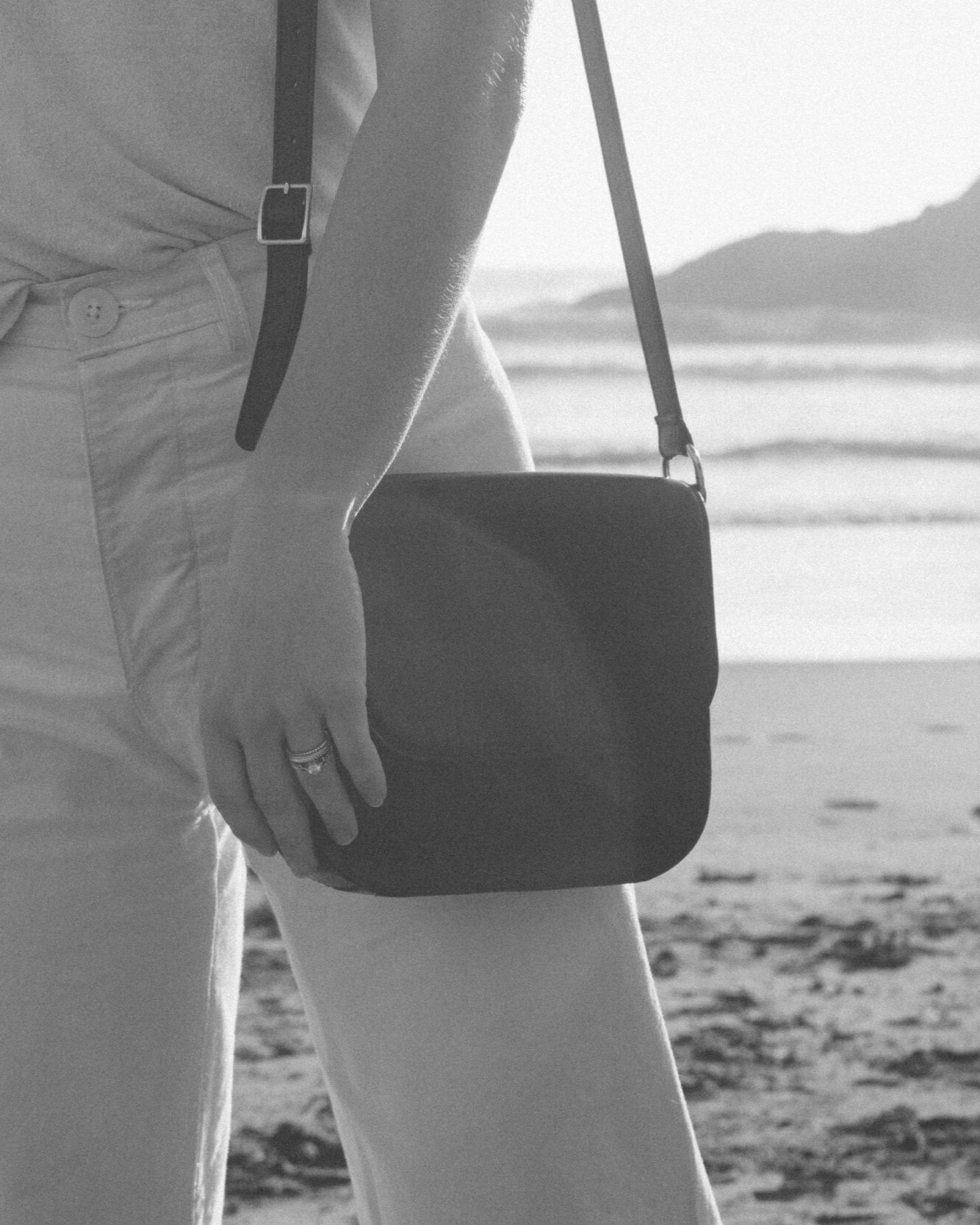 Person holding a black bag on a beach with a blurred background