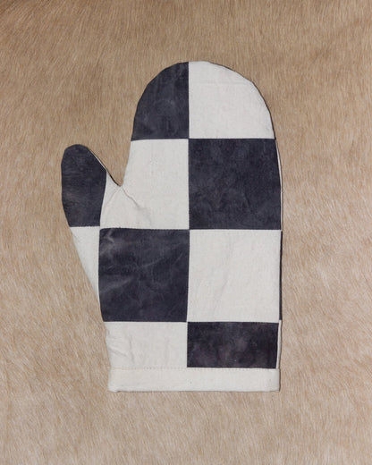 Black and white checkered oven mitt on a beige surface