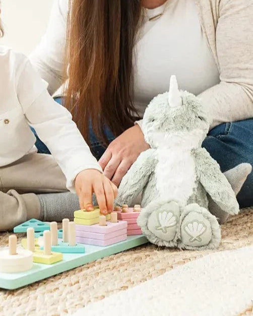 Woman and child playing with a colorful educational toy on a carpeted floor.