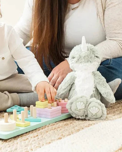 Woman and child playing with a colorful educational toy on a carpeted floor.